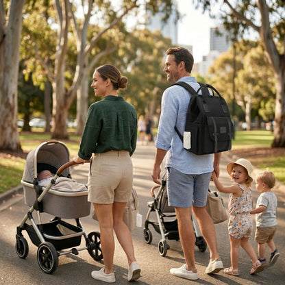 Family at the park dad wearing black nappy bag, mom pushing pram