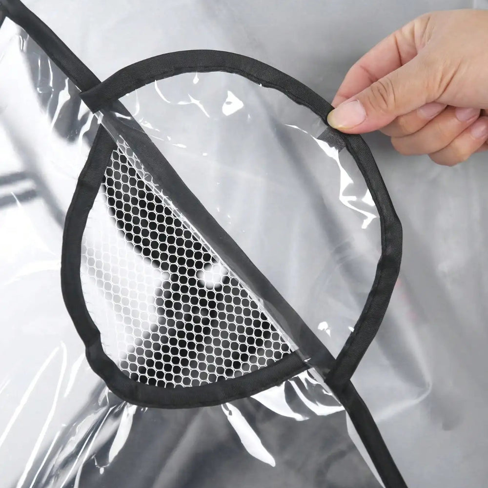 Hand holding a black mesh ventilation panel against a clear EVA pram rain cover — showing breathability detail