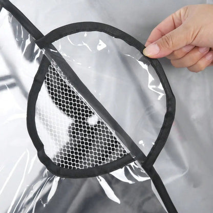 Hand holding a black mesh ventilation panel against a clear EVA pram rain cover — showing breathability detail