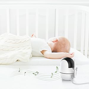 Baby lying in a crib with a white blanket and a black and silver camera device on a white background