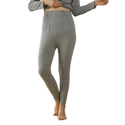 Person wearing gray lounge pants standing in a living room with a beige sofa.
