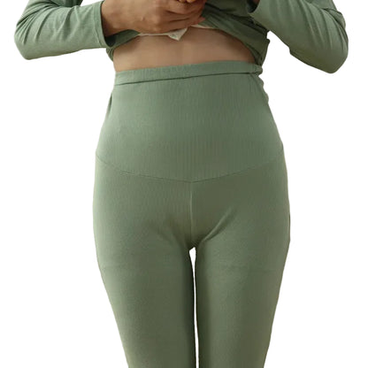 person wearing green ribbed leggings and top in a room with a couch and chair.