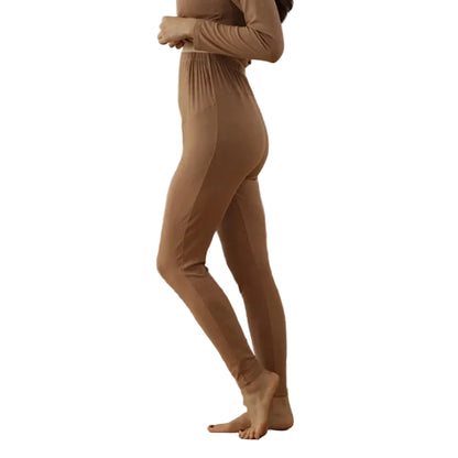 Person wearing a nude bodysuit standing in a room with a beige sofa.